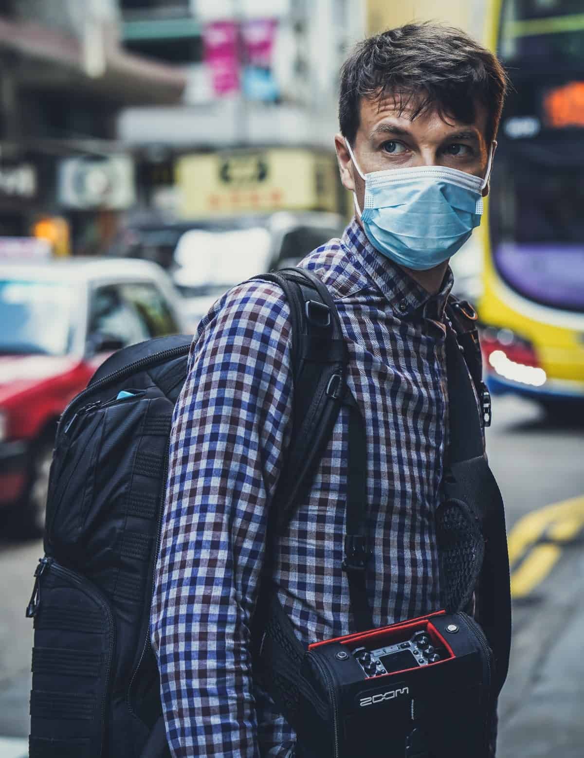 A man wearing a facemask and crossing the street.