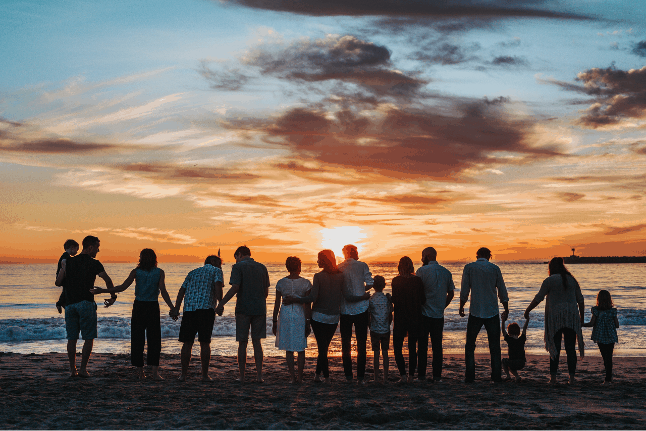 A large family on a beach at sunset.