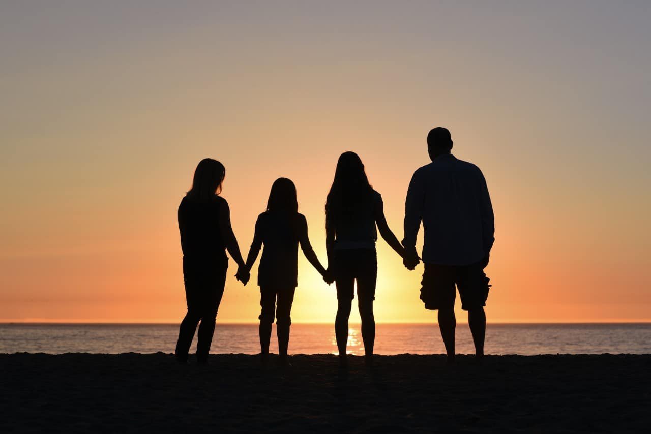 Silhouette of a mom, dad, and two daughters overlooking the ocean.