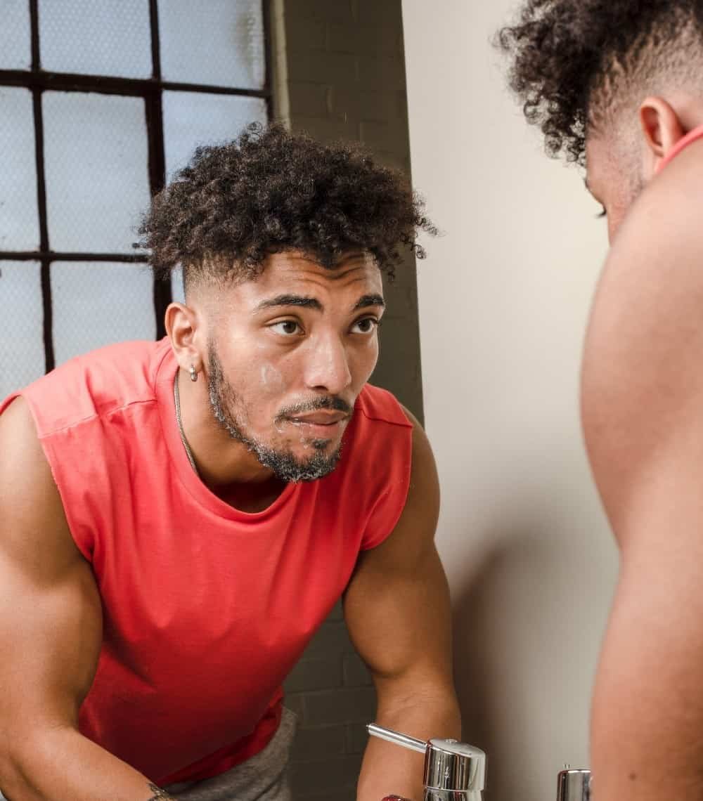 Man washing face looking in mirror