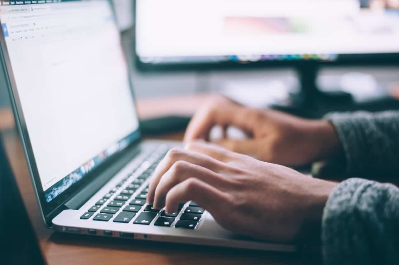 A man's hands typing on a laptop.