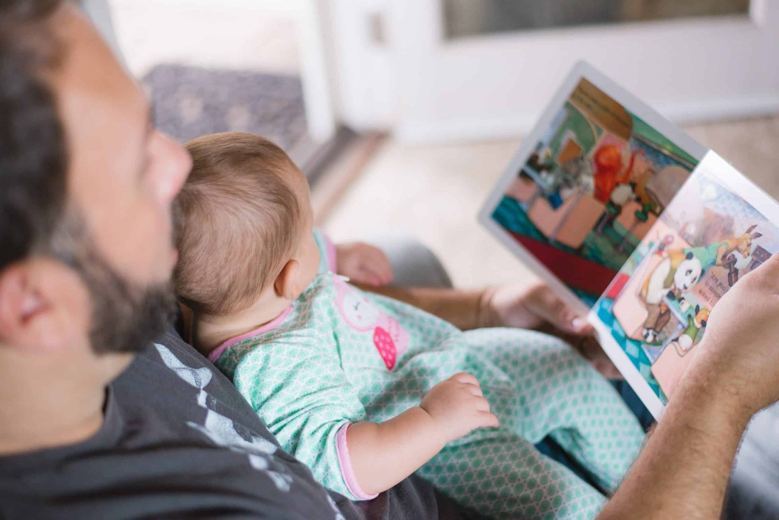 father reading a book to his child who sitting in his lap